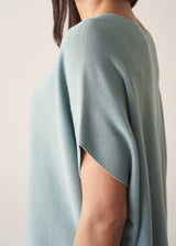 Woman wearing light sage sweater with blue jeans