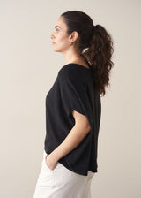 Woman wearing black relaxed sleeve sweater and white barrel leg jeans