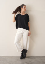 Woman wearing black relaxed sleeve sweater and white barrel leg jeans