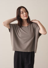 Woman wearing light stone sleeveless knit sweater with black jersey trousers