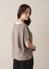 Woman wearing light stone sleeveless knit sweater with black jersey trousers