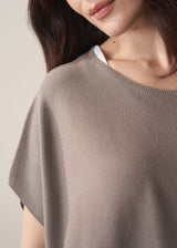 Woman wearing light stone sleeveless knit sweater with black jersey trousers
