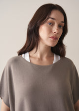Woman wearing light stone sleeveless knit sweater with black jersey trousers