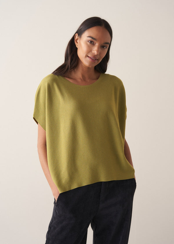 Woman wearing olive green short sleeve sweater against a plain background