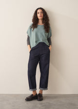 Woman wearing sage short sleeve draped sweater with blue jeans