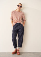 Woman wearing burnt orange and oatmeal striped fine knit sweater with blue denim trousers