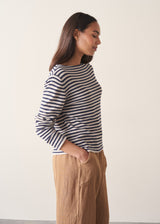 Woman wearing dark grey and off white stripe knit sweater and brown linen trousers