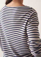 Woman wearing dark grey and off white stripe knit sweater and brown linen trousers