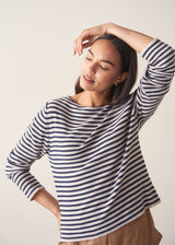 Woman wearing dark grey and off white stripe knit sweater and brown linen trousers