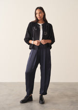 Woman wearing a three-quarter sleeve black devore jacquard top with dark blue satin trousers against a plain background