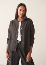 A woman wearing a dark check boxy jacket with barrel leg check trousers and a white t-shirt.