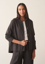 A woman wearing a dark check boxy jacket with barrel leg check trousers and a white t-shirt.