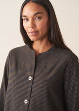 A woman wearing a dark check boxy jacket with barrel leg check trousers and a white t-shirt.