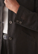 A woman wearing a dark check boxy jacket with barrel leg check trousers and a white t-shirt.