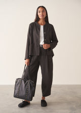A woman wearing a dark check boxy jacket with barrel leg check trousers and a white t-shirt.
