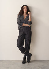 Woman wearing grey jumper and dark blue black straight leg denim jeans