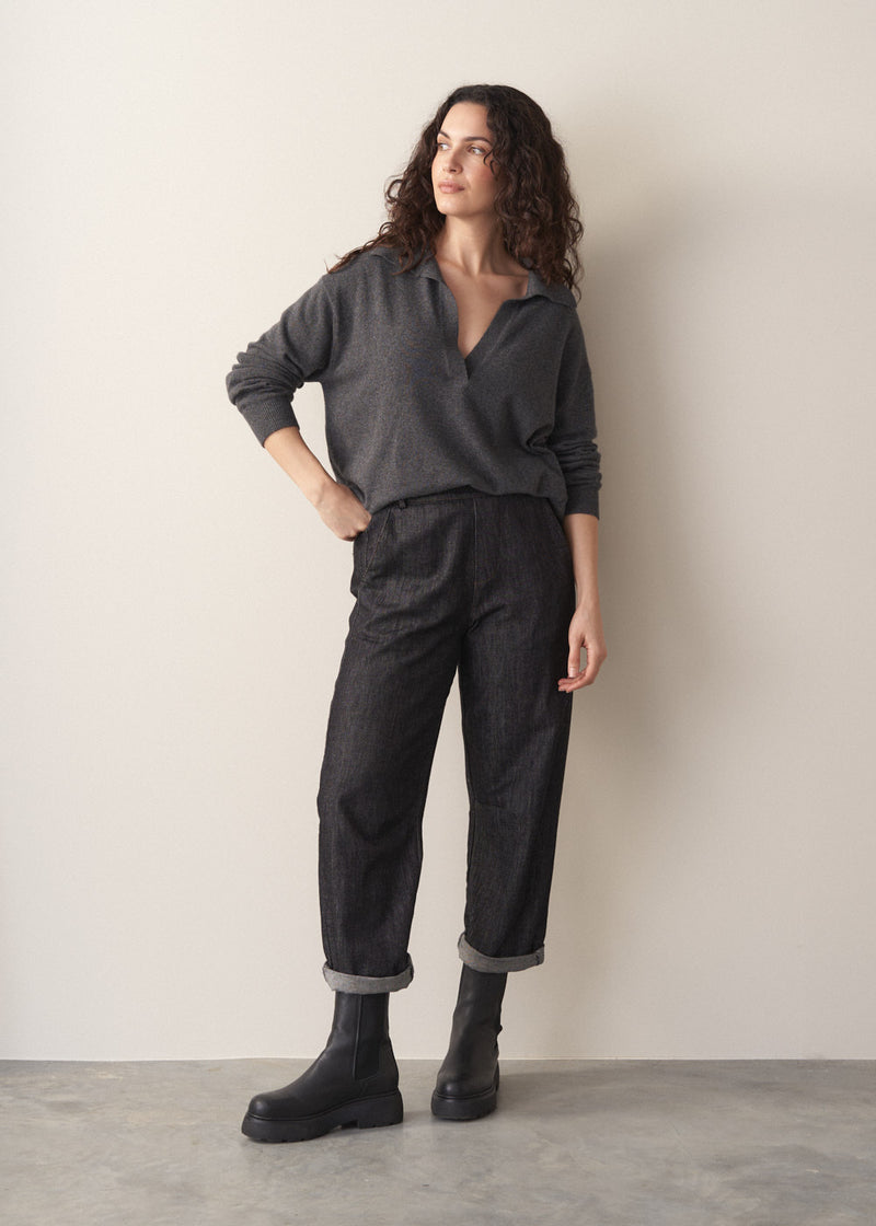 Woman wearing grey jumper and dark blue black straight leg denim jeans