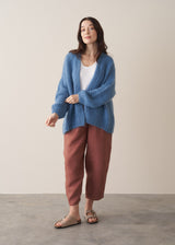 Woman wearing chunky blue cardigan and brown linen trousers