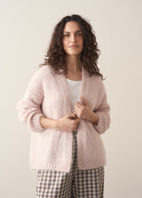 Woman wearing an oversized blush pink chunky knit cardigan with checked trousers 