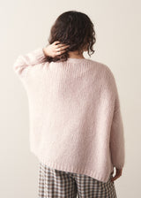 Woman wearing an oversized blush pink chunky knit cardigan with checked trousers 