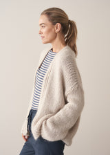 Woman wearing oversized chunky cardigan in oatmeal with dark grey blue joggers and stripe knit top