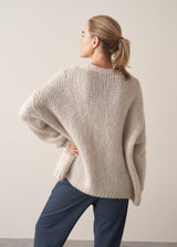 Woman wearing oversized chunky cardigan in oatmeal with dark grey blue joggers and stripe knit top