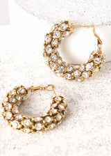 A pair of large crystal hoop earrings on concrete background