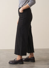 Woman wearing striped sweater and black wide leg cropped trousers