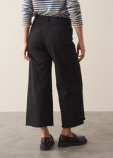 Woman wearing striped sweater and black wide leg cropped trousers