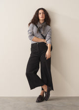 Woman wearing striped sweater and black wide leg cropped trousers