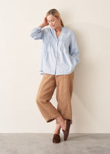 Woman wearing blue pintuck shirt with beige linen trousers