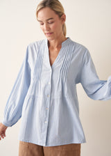Woman wearing blue pintuck shirt with beige linen trousers