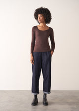 Woman wearing a brown long-sleeve cashmere blend top and blue jeans against a white background