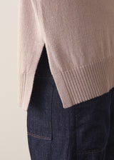 Woman wearing a beige sleeveless button up cardigan with blue jeans 