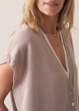 Woman wearing a beige sleeveless button up cardigan with blue jeans 