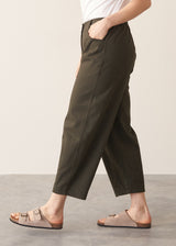 Woman wearing white t-shirt and dark green barrel leg trousers