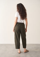 Woman wearing white t-shirt and dark green barrel leg trousers
