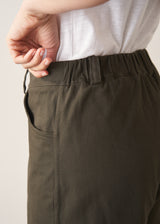 Woman wearing white t-shirt and dark green barrel leg trousers