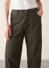 Woman wearing white t-shirt and dark green barrel leg trousers