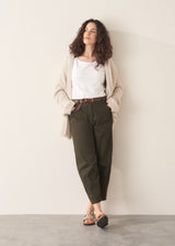 Woman wearing white t-shirt and dark green barrel leg trousers