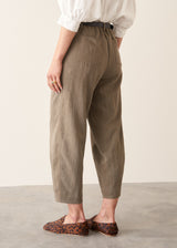 Woman wearing light khaki trousers with a white, puff sleeve shirt and brown leopard loafers.