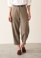 Woman wearing light khaki trousers with a white, puff sleeve shirt and brown leopard loafers.