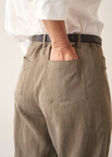 Woman wearing light khaki trousers with a white, puff sleeve shirt and brown leopard loafers.