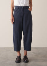 Woman wearing a white cropped linen shirt and navy barrel leg trousers