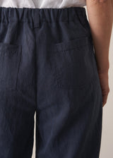 Woman wearing a white cropped linen shirt and navy barrel leg trousers