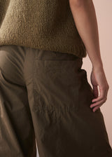 Person wearing a khaki knitted sweater and matching wide leg cargo trousers against a beige background