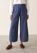 A woman wearing a white long-sleeve embroidered blouse and blue wide-leg cargo trousers, paired with brown loafers.