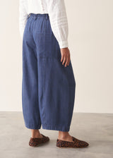 A woman wearing a white long-sleeve embroidered blouse and blue wide-leg cargo trousers, paired with brown loafers.