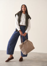 A woman wearing a white long-sleeve embroidered blouse and blue wide-leg cargo trousers, paired with brown loafers.