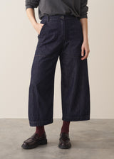 Woman wearing a grey sweater and dark blue wide leg cargo jeans and brown loafers